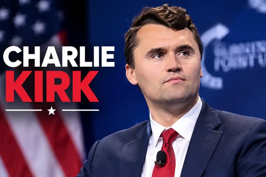 Charlie Kirk in a suit and red tie speaking at a political event with American flag